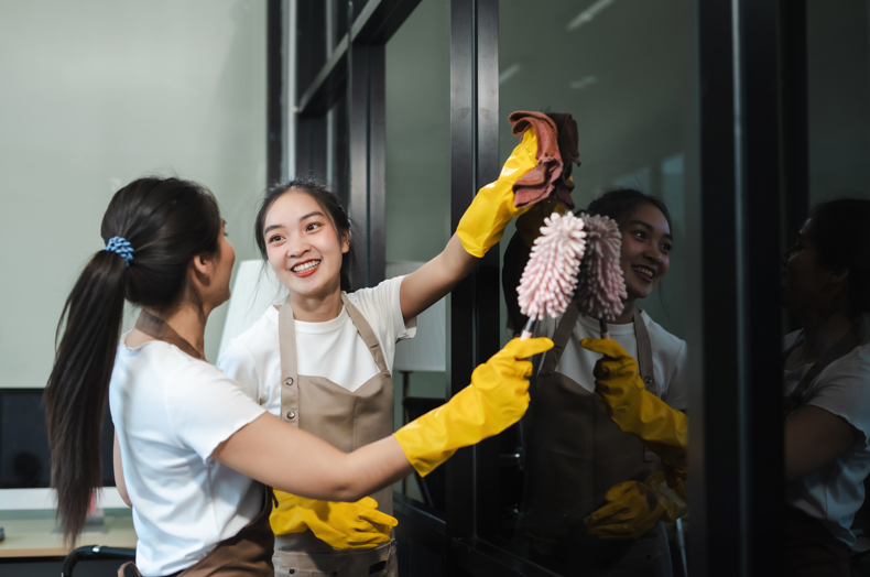 Two women cleaning windows in a business to ensure good first impressions