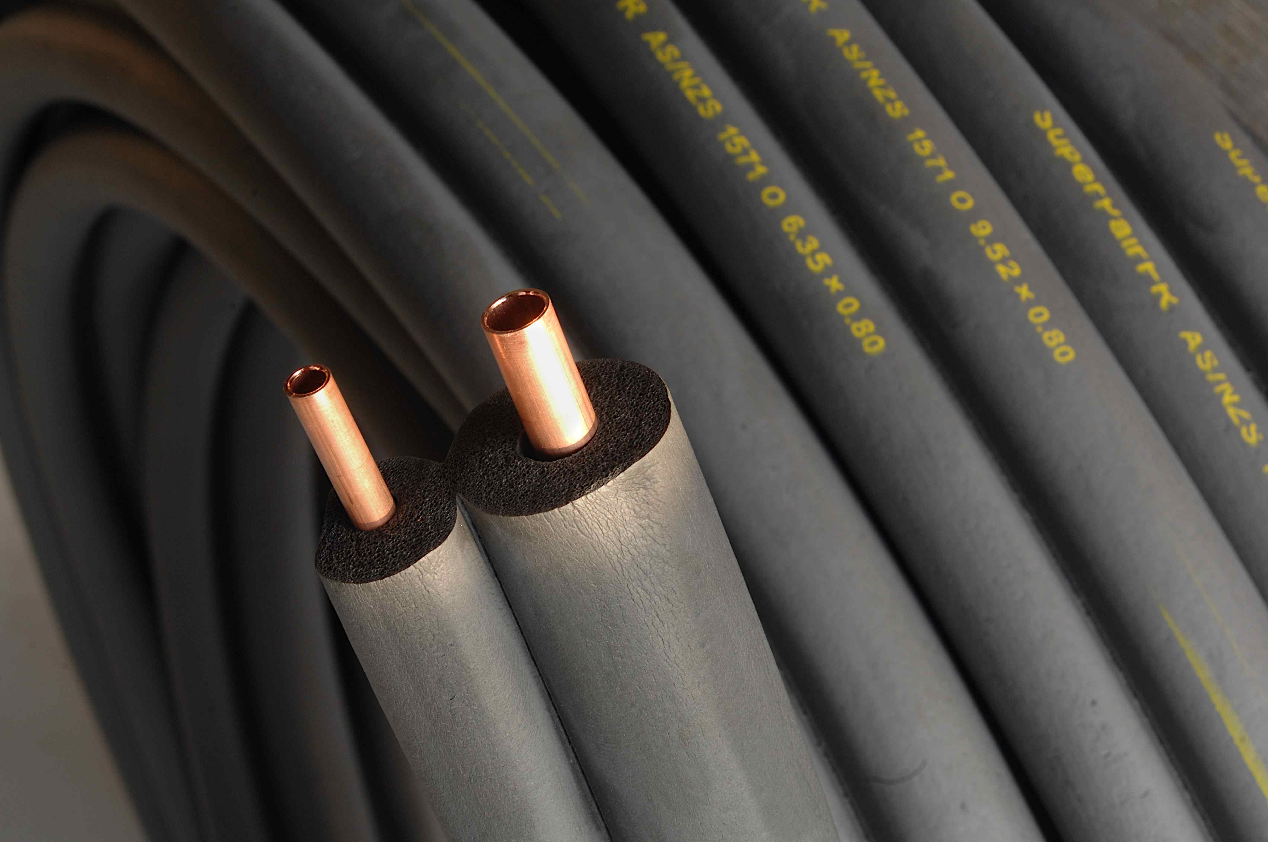 Insulated copper pipes with printed specifications, commonly used in HVAC systems.