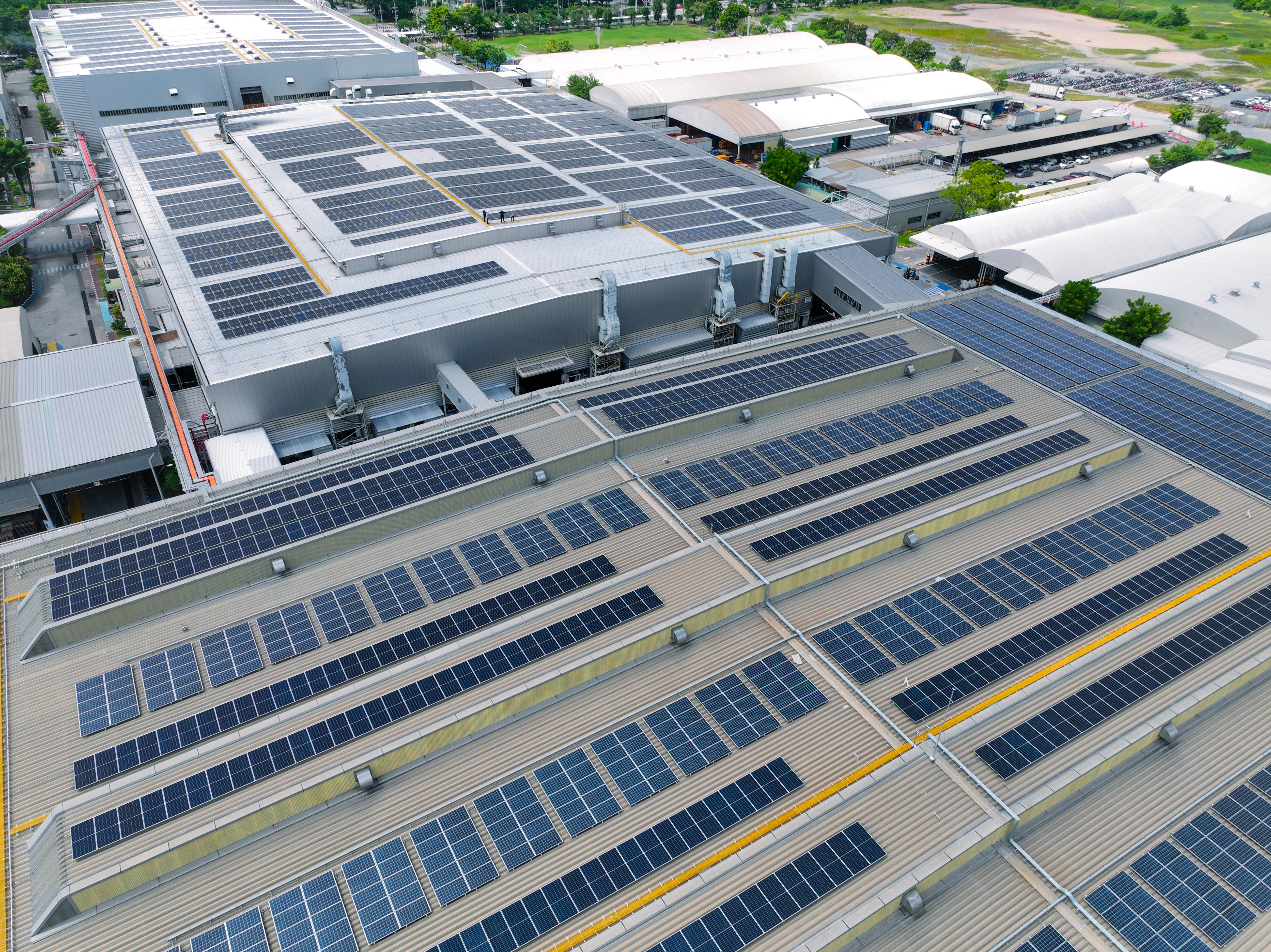 Aerial view of large industrial buildings with solar panels installed across multiple rooftops.