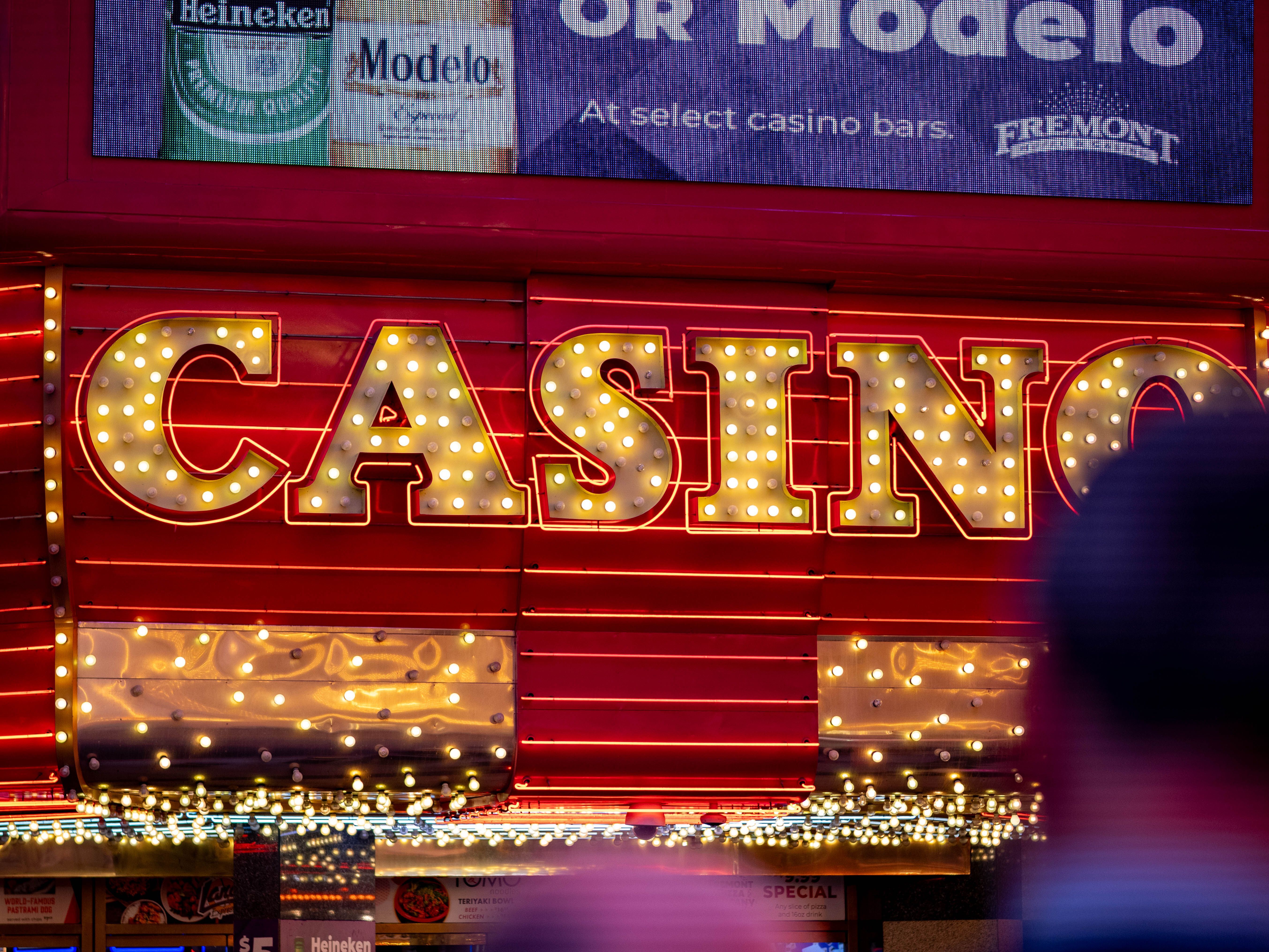 A glowing casino sign shines brightly at night in a busy cityscape.