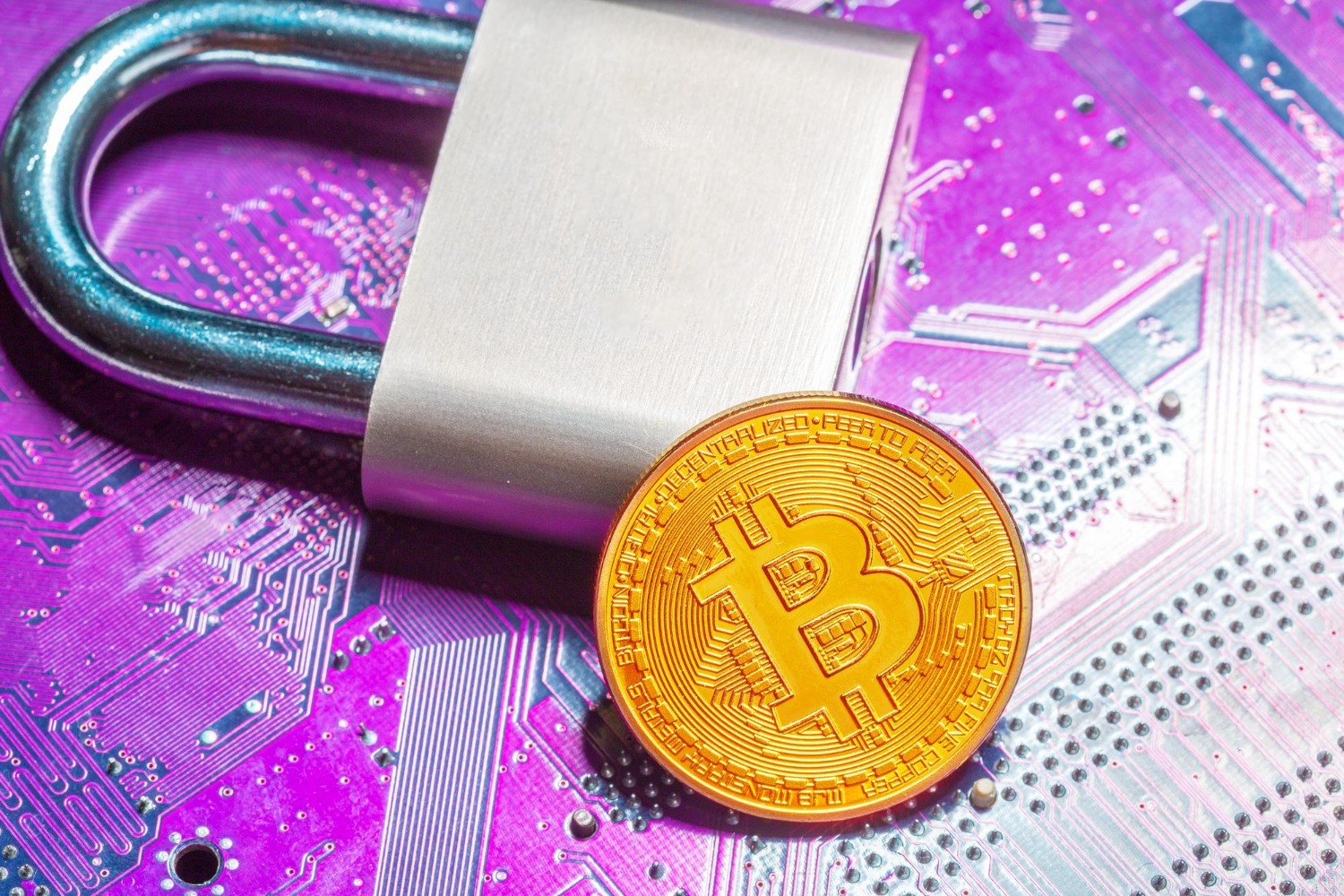 A gold Bitcoin coin and a silver padlock resting on a glowing purple circuit board.