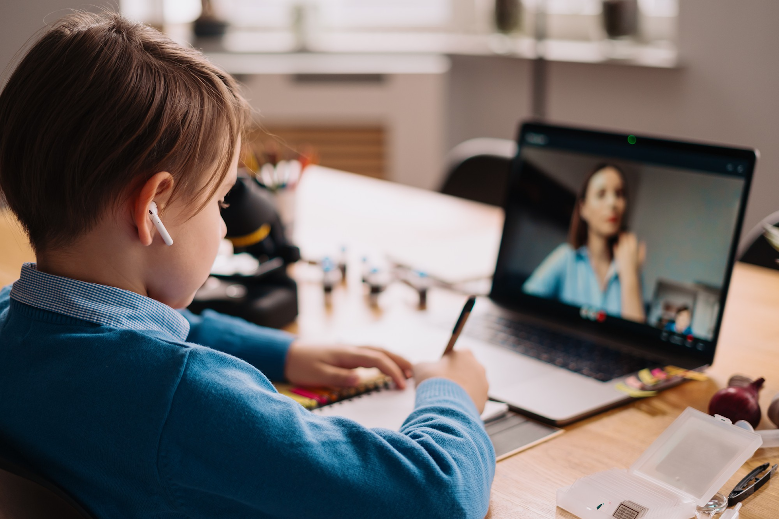 A preteen boy uses a laptop to make a video call with his teacher