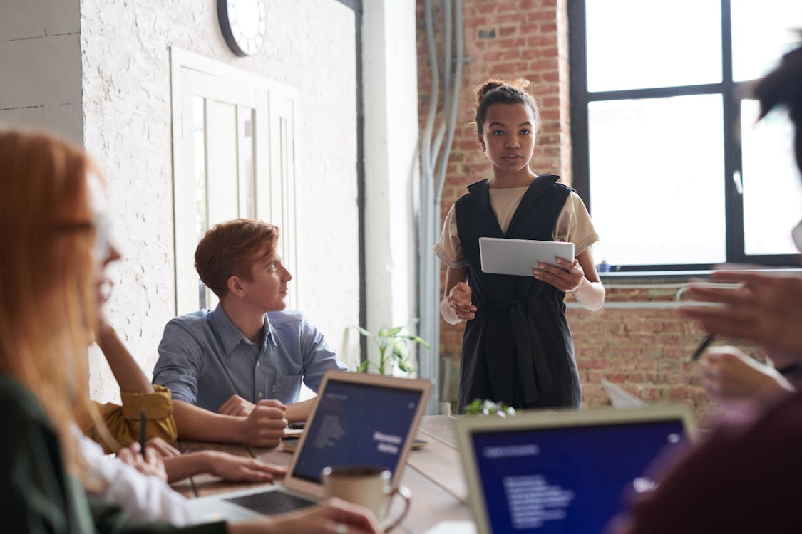 A woman presents to a group of colleagues in an office meeting.