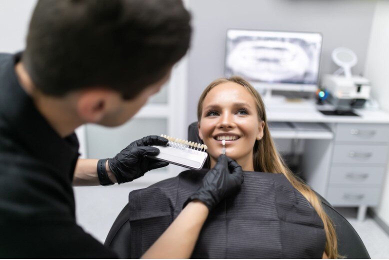 Beautiful european woman smile with healthy teeth whitening. Set of implants with various shades of tone