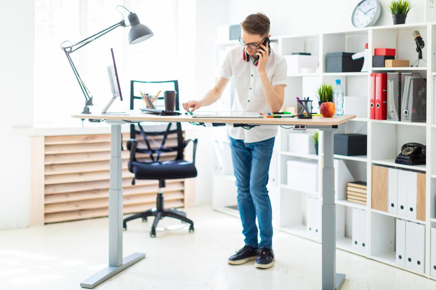 A man standing in front of the standing tabl ewhile making a phone call