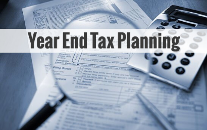 Year end tax planning written over magnifying glass over papers and calculator