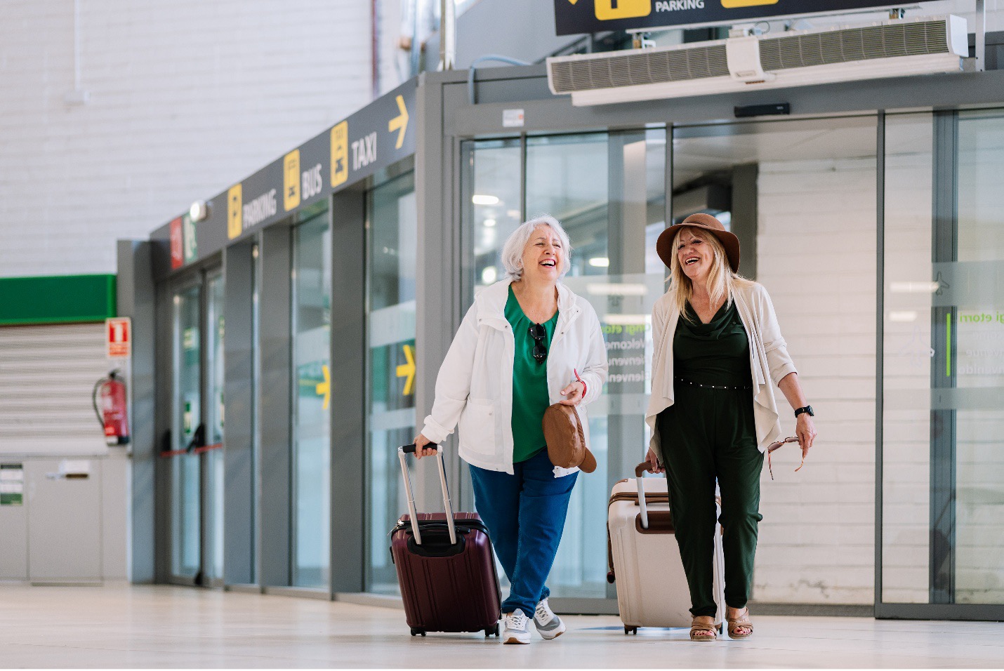 Effective Airport PA Systems: Two happy women walking through airport with cases