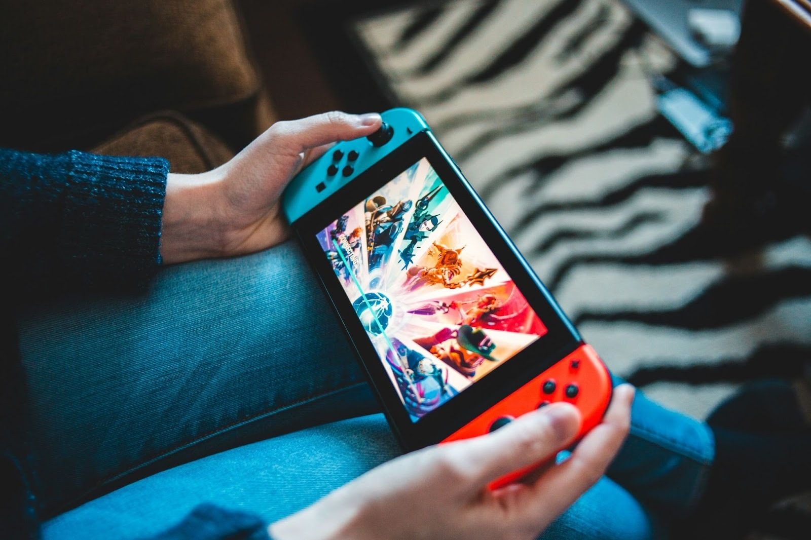 Hands holding a Nintendo Switch console displaying a colorful fighting game.