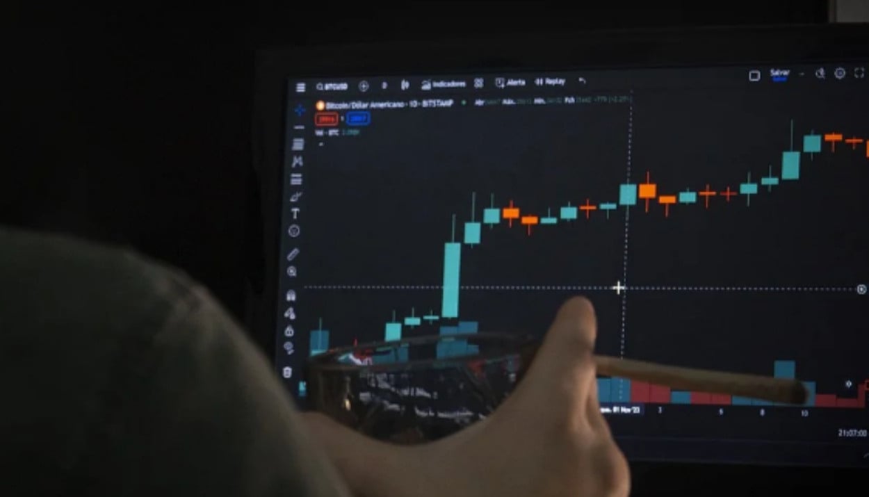 A man looking at a computer screen that has a stock graph