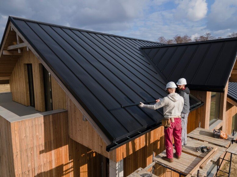 2 working men holding metal pipe on the roofs