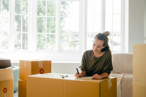 woman-signing-box-near-large-window-in-sunlight-at-home