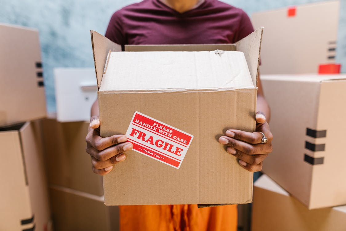 Person carrying box labelled Fragile