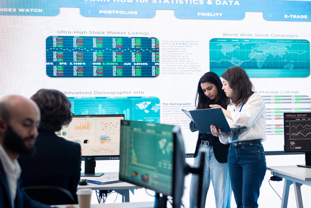 People looking at multiple large screens filled with financial charts and data.