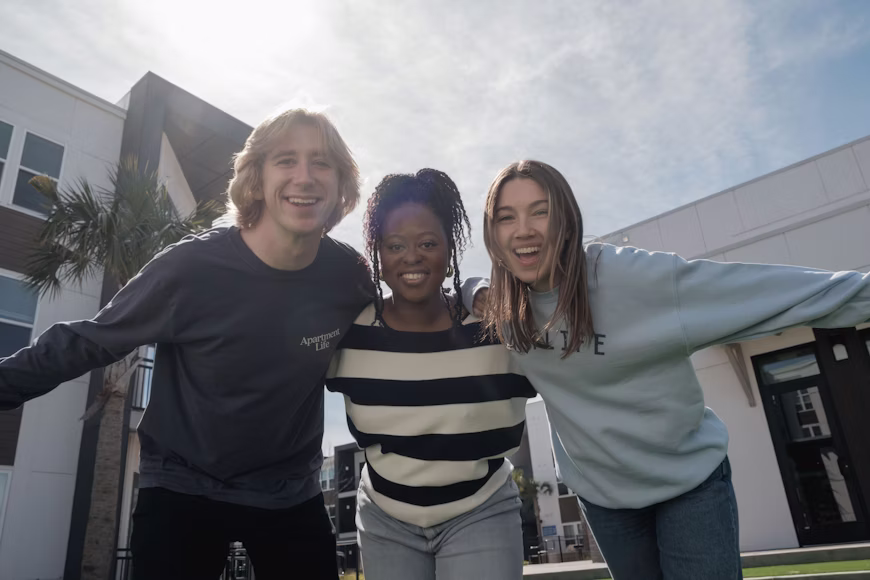 Three smiling friends with arms around each other