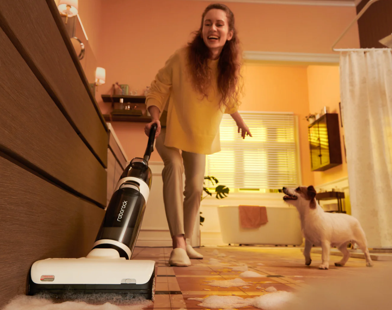Woman is happily vacuum cleaning with her dog
