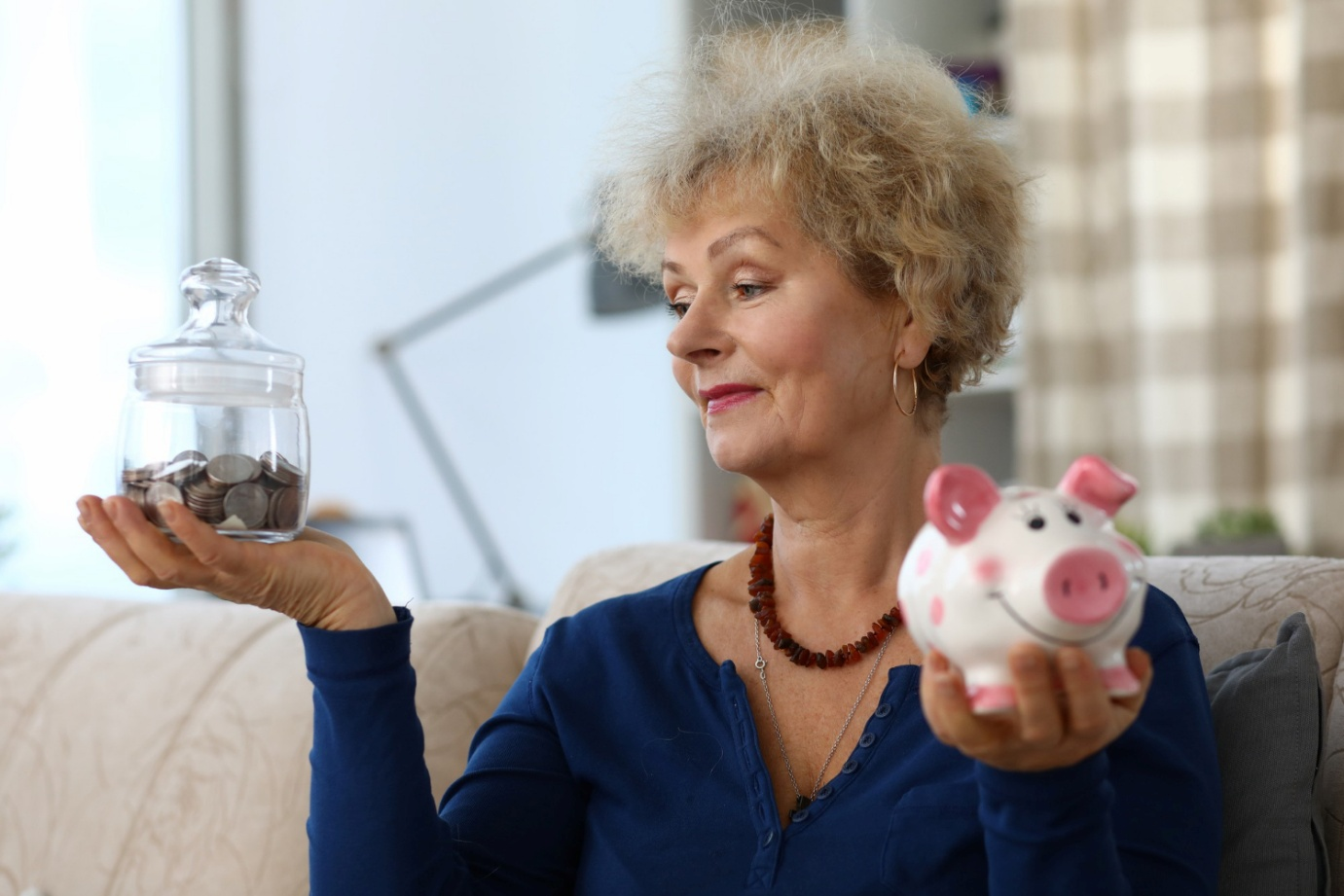 Women comparing a jar full of coins with piggy bank