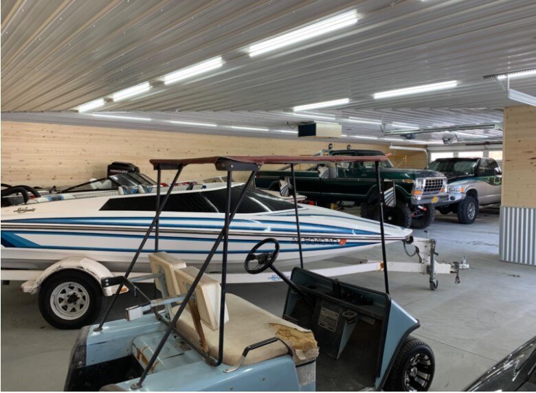 a boat, golf car, 2 cars in a garage