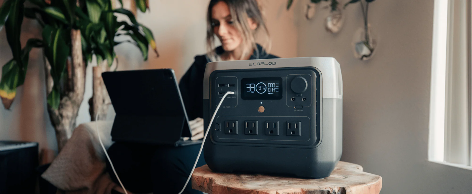 a woman using a laptop thats plug into portable power station