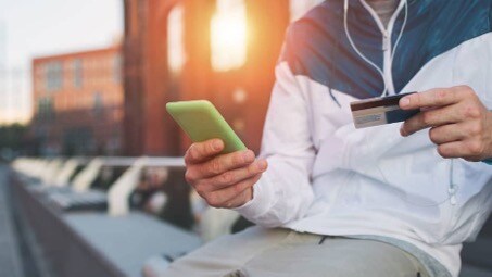 Photo of person holding a phone in one hand a credit card in the other