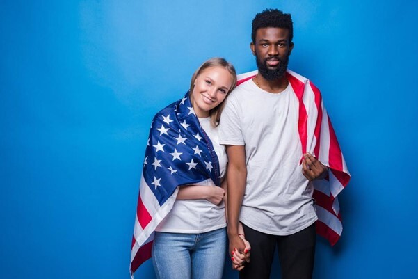 Man and woman covered with american flag isolated on blue wall
