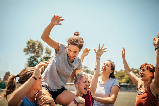 Photo of women's sports team cheering and lifting one team member on their shoulders