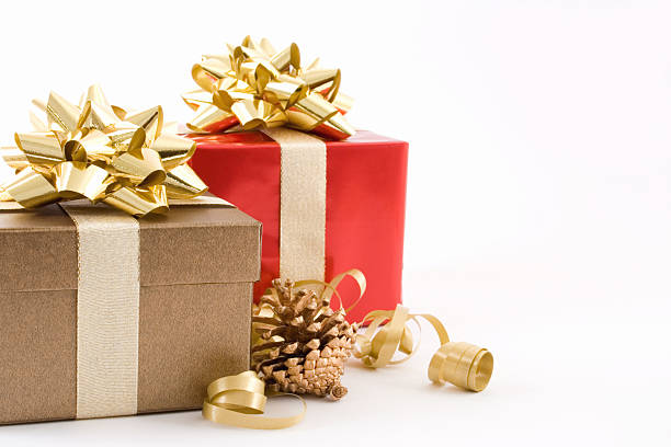types of customized gift boxes - Image of one gold gift box and one red both tied with gold ribbon a pinecone sprayed gold and some gold ribbon curls in the foreground background is void white