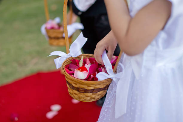 Close up on flower petal basket being held by young girl in silk flower girl dress