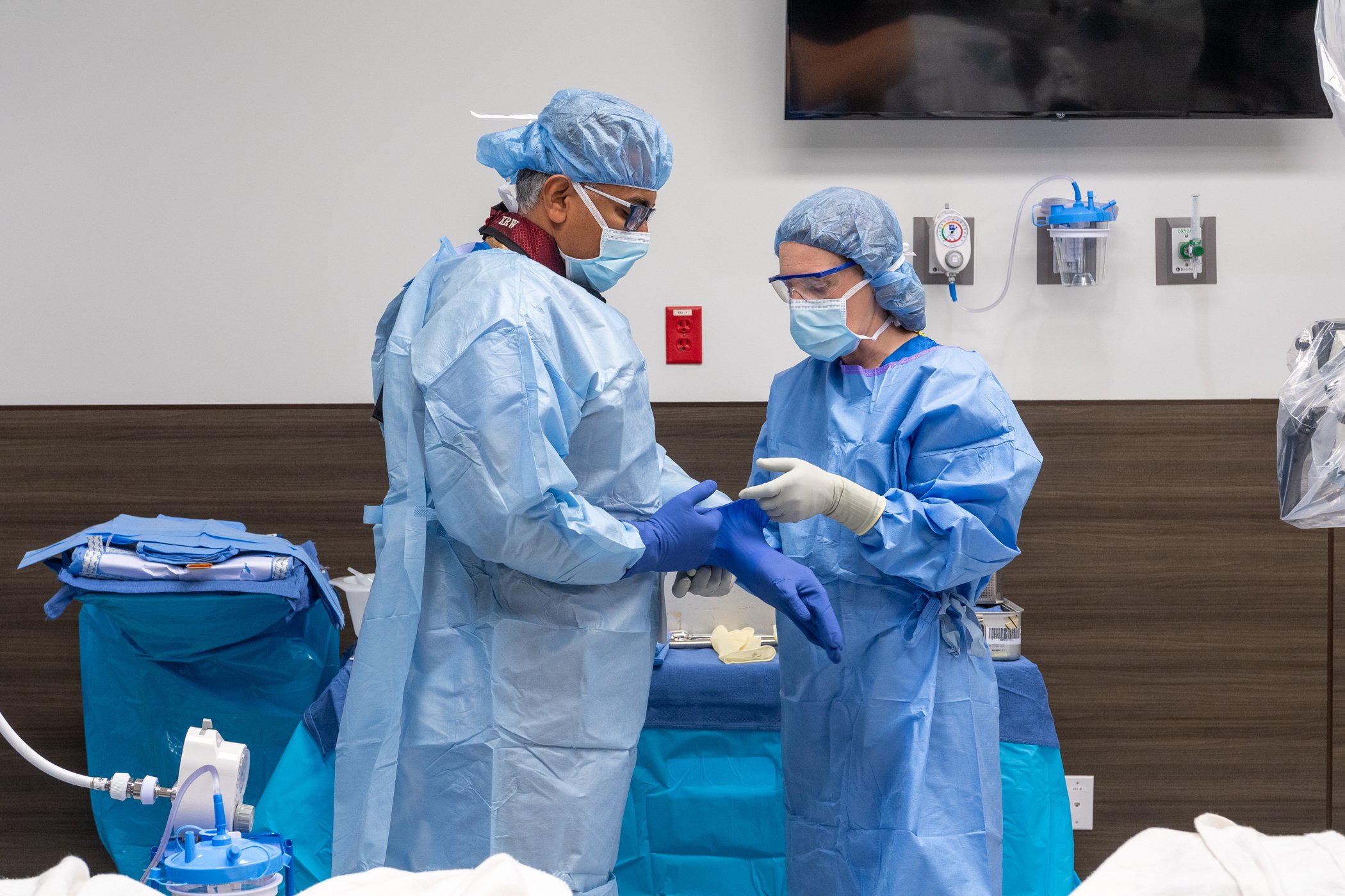 a doctor is getting help from a nurse to prep for operation