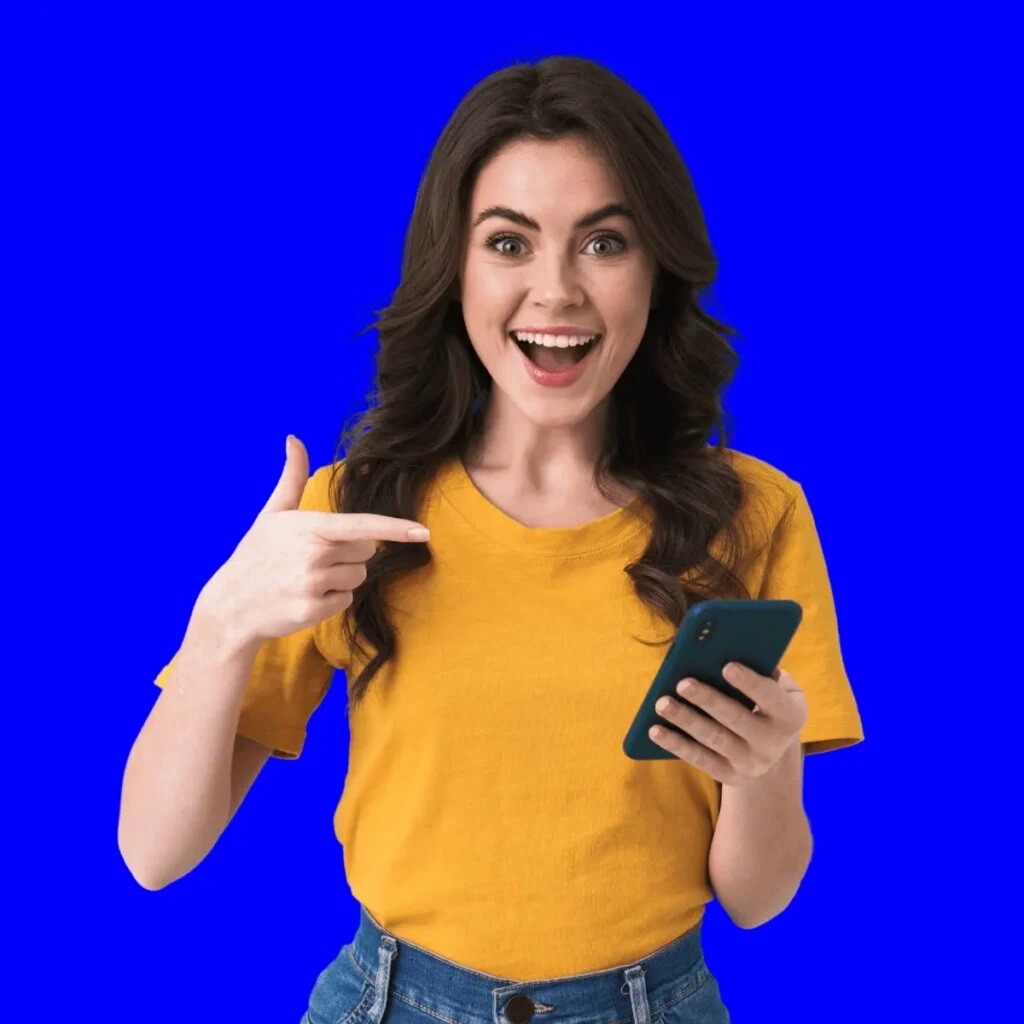 smiling woman holding phone in one hand and pointing at it with the other on a royal blue background