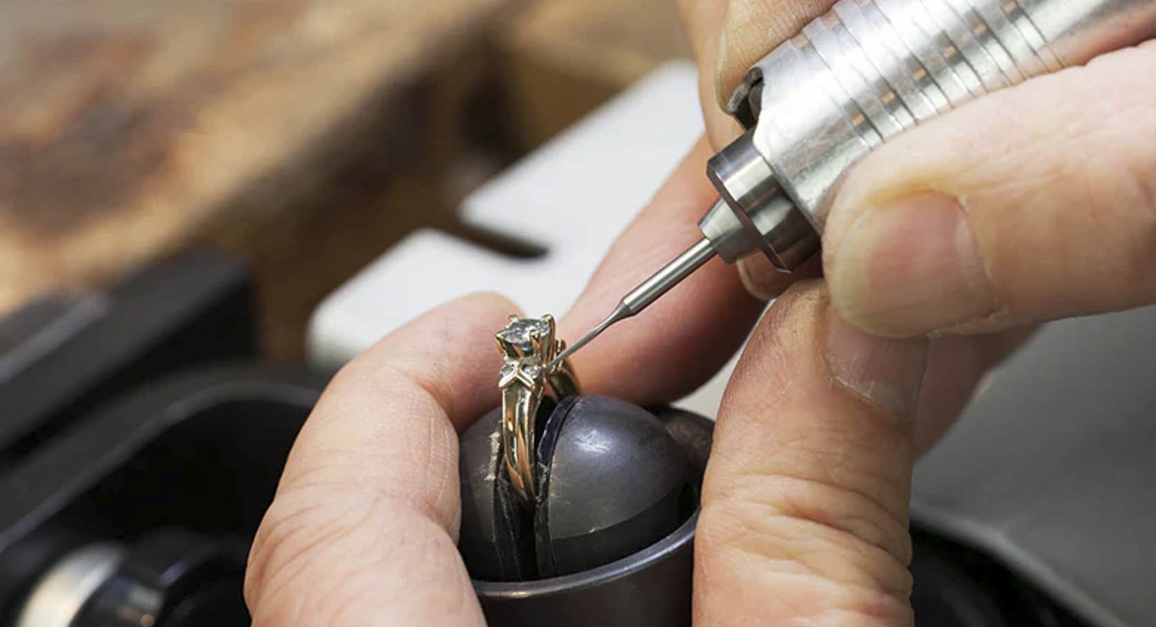 Photo close up of jeweler's hands working on gold diamond ring